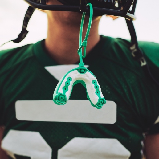 Athletic mouthguard hanging from helmet of football player
