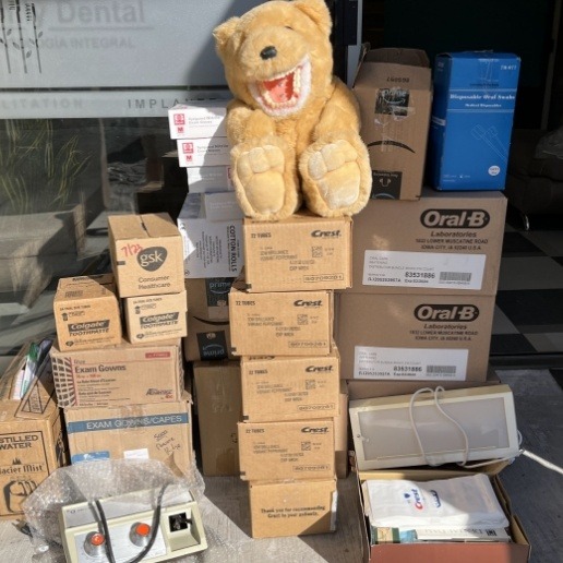 Pile of several boxes with a teddy bear wearing false teeth on top of pile