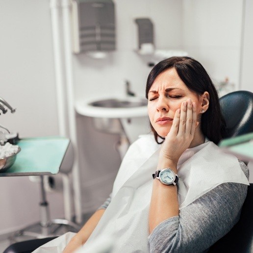 Woman holding her face in pain while visiting emergency dentist in Hammond