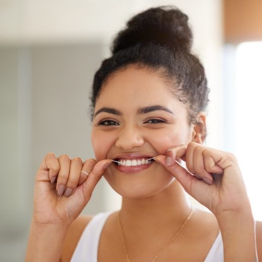 Young woman grinning while flossing her teeth