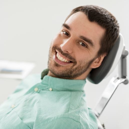 Man in light green shirt smiling in dental chair