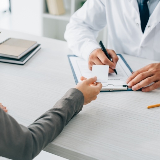 Person handing credit card to a dental team member holding a clipboard