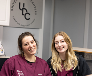 Two smiling dental team members at front desk of Hammond dental office