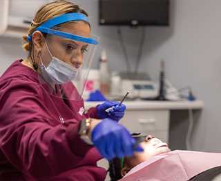 Dental team member reaching for a dental tool while treating a patient