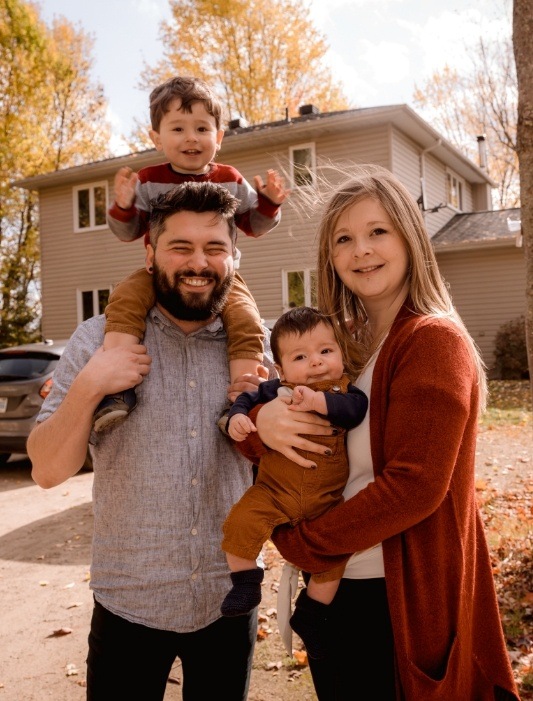 Family of four smiling in front yard after receiving dental services in Hammond