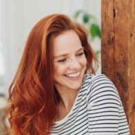 Woman with red hair and striped blouse grinning 