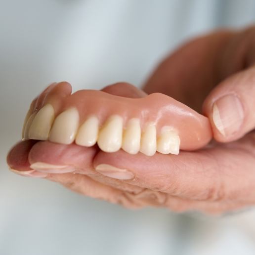 Dentist holding a full upper denture in their hand