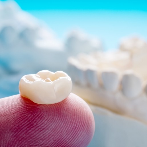 Dentist holding a dental crown in Hammond on their finger