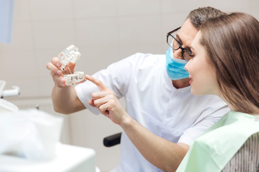 Dentist showing sample implant to patient during consultation